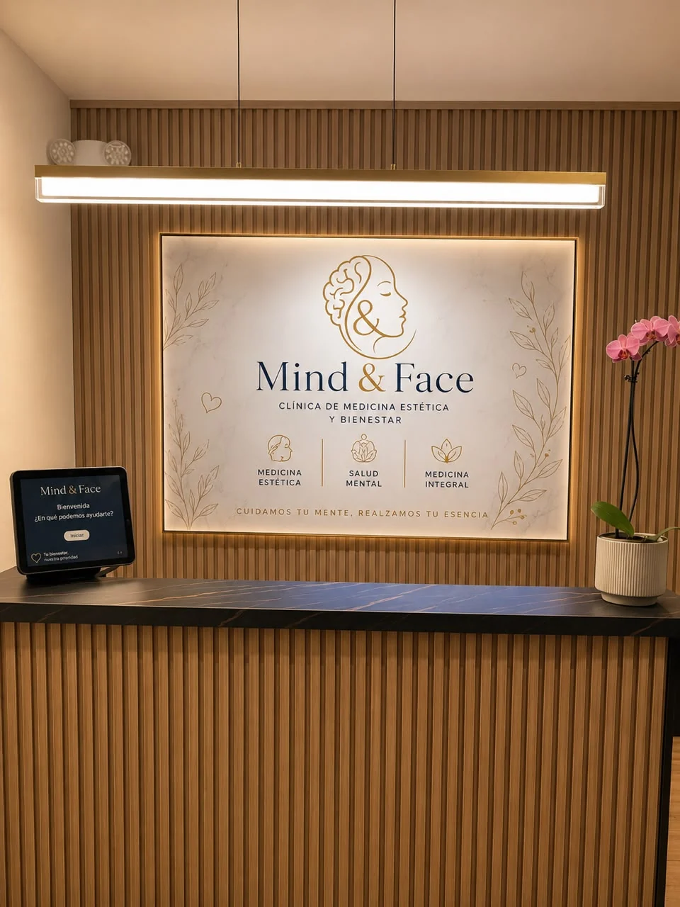 Recepción de Mind&Face: mostrador de madera y mármol oscuro con el logotipo del centro iluminado sobre la pared.